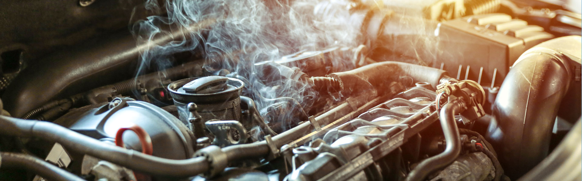Smoke or steam rising from an overheated car engine bay.