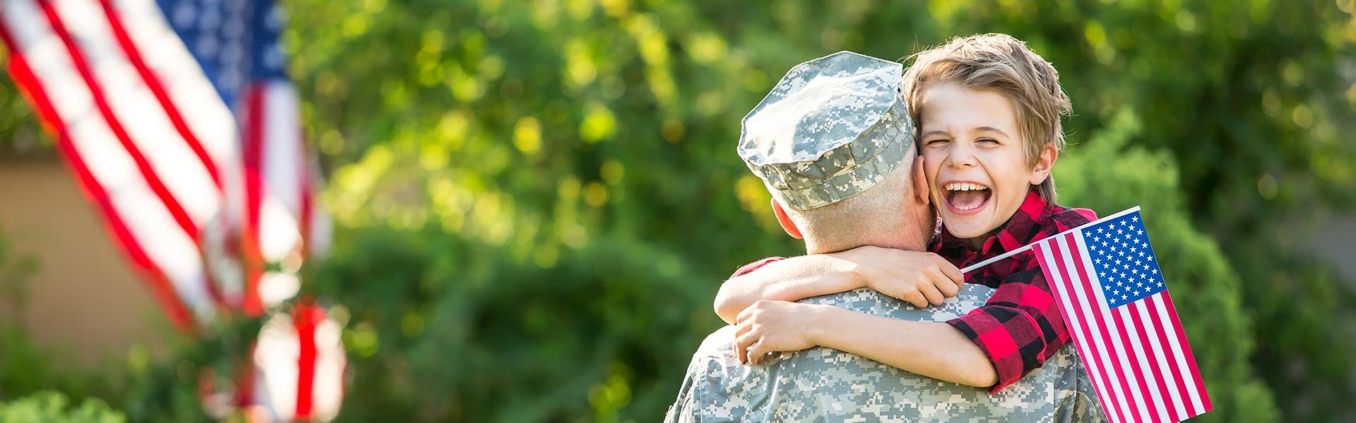 A kid is playing with a military man, holding a flag in hand.